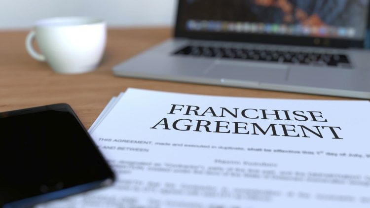 The words franchise agreement on a contract on a table. 