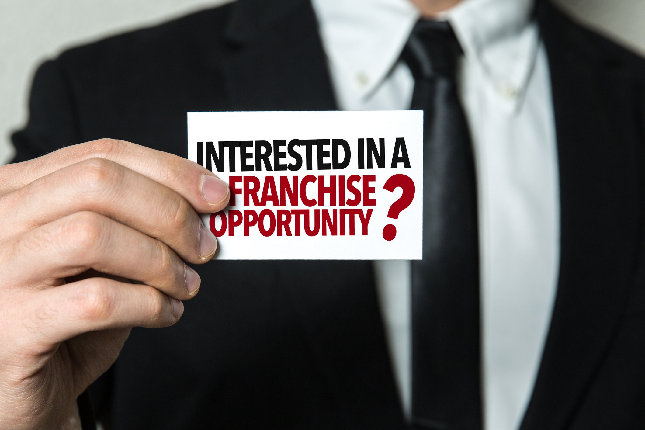 A person holding up a card that says Interested in a franchise opportunity?