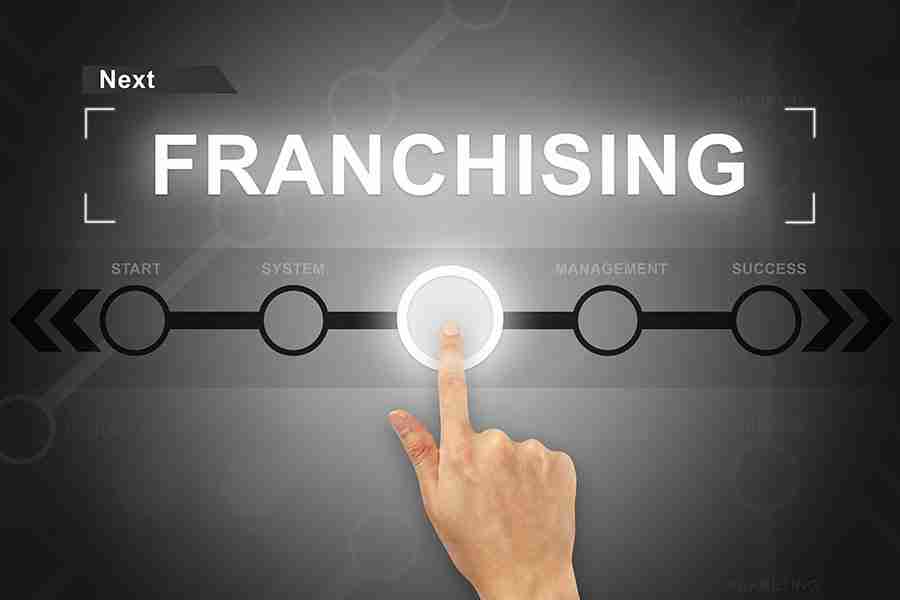 The word franchising in neon white color with a hand touching a button