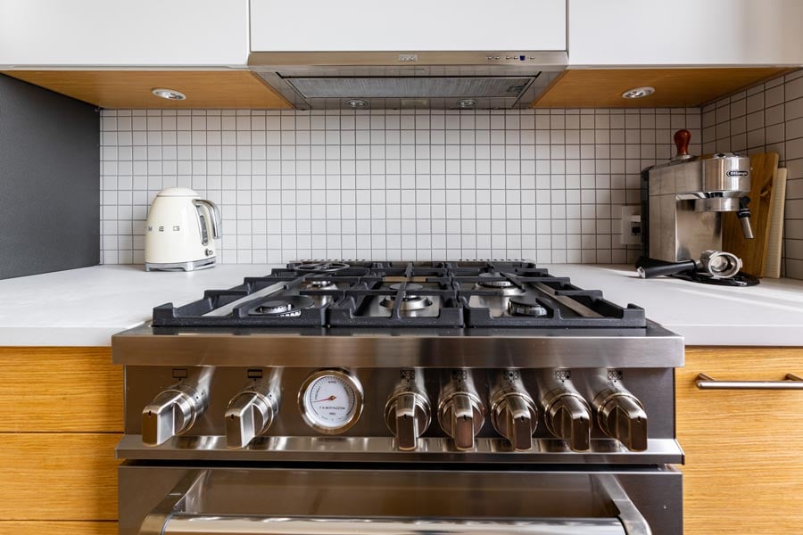 Gas stove top with a kettle to the left counter and espresso machine on the right counter.