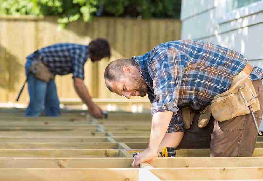 Two men working on the framing of a floor. 