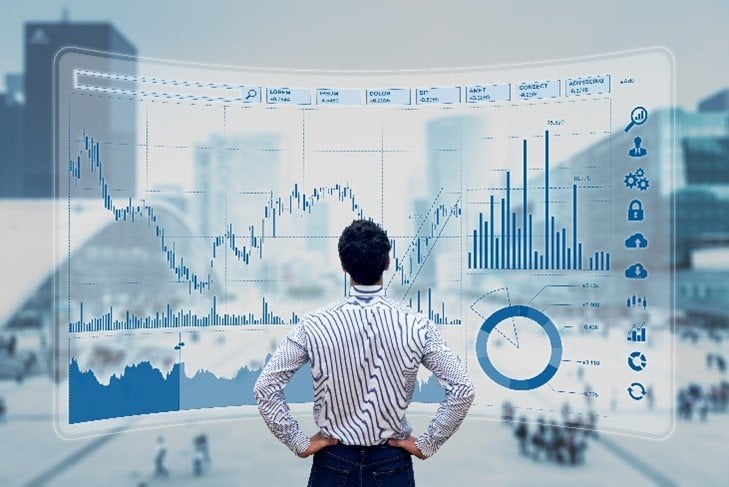 A man standing in front of a window screen with a lot of graphs. 