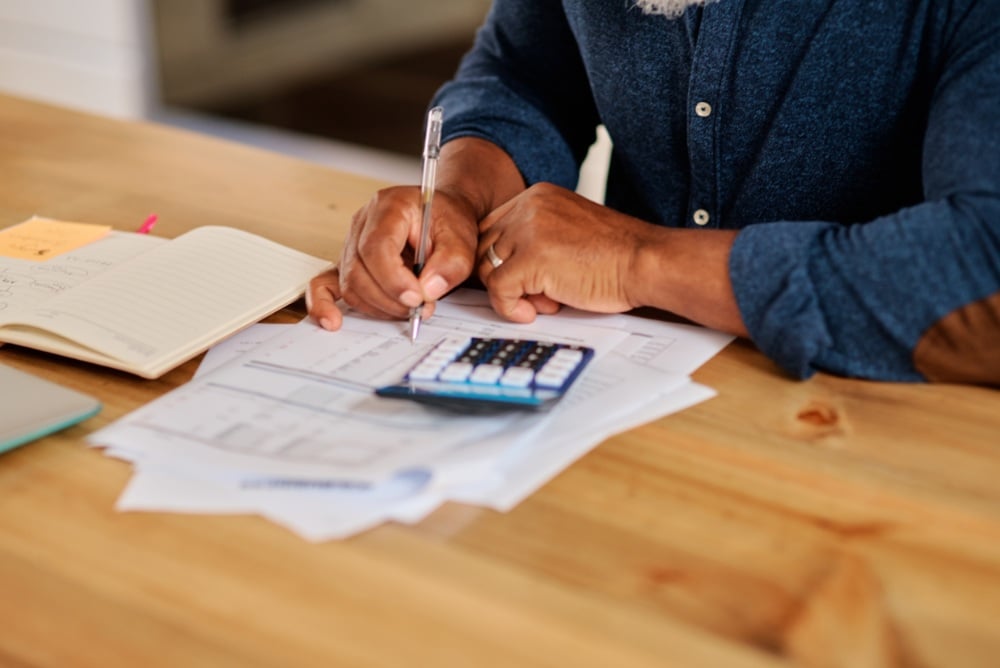 A person working on finance papers with a calculator.