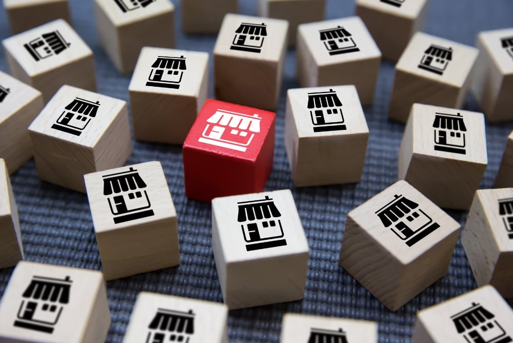 Regular colored wooden blocks with home symbols on them with one red wooden block in the center.