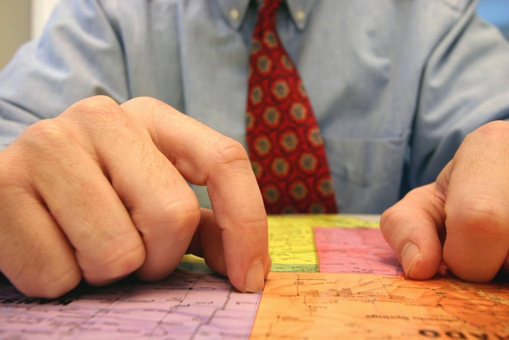 Zoomed in on a man's hands that are resting on a map. 